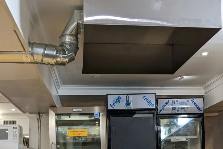 Metal extraction canopy and connected ductwork above a kitchen preparation area