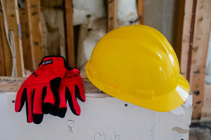 Yellow hard hat and red protective gloves on a construction work surface