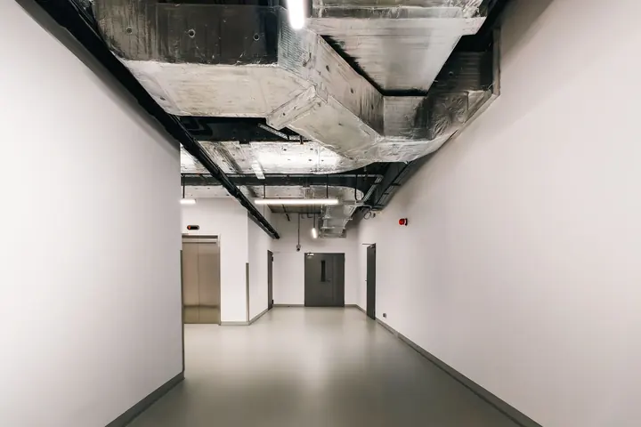 Exposed insulated ventilation ductwork in a modern industrial corridor