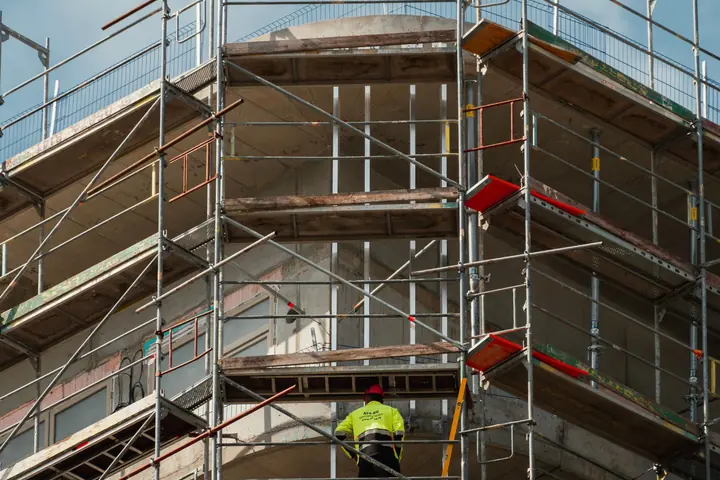 Construction worker in high-visibility clothing on building scaffolding