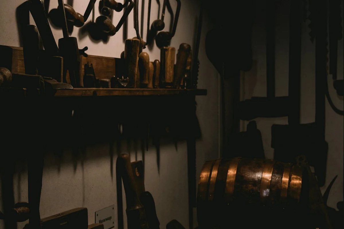 Hand tools stored on shelves and hooks in a dimly lit workshop