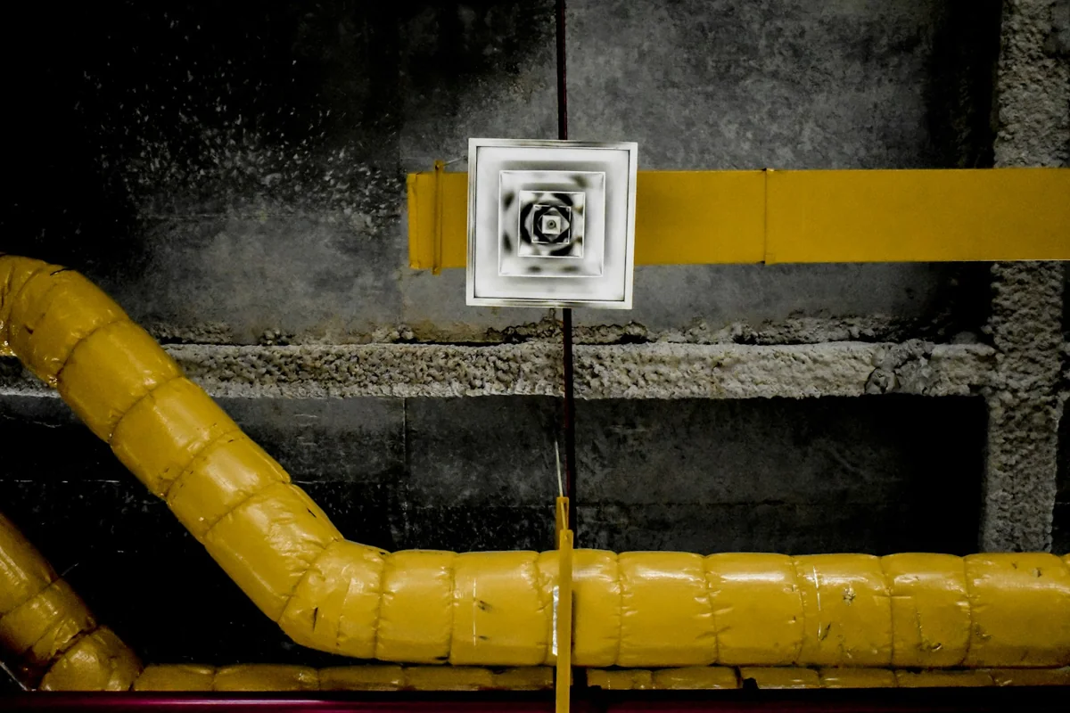 Ventilation terminal and insulated pipes on an exposed services ceiling