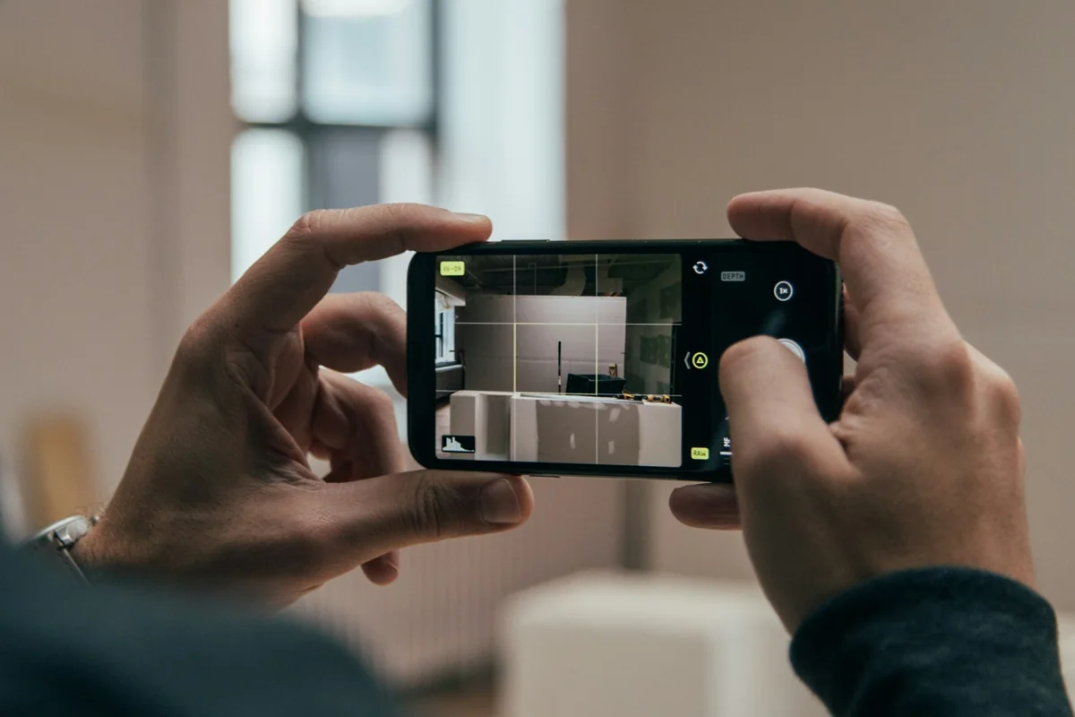 Hands using a smartphone camera to record an unfinished building interior