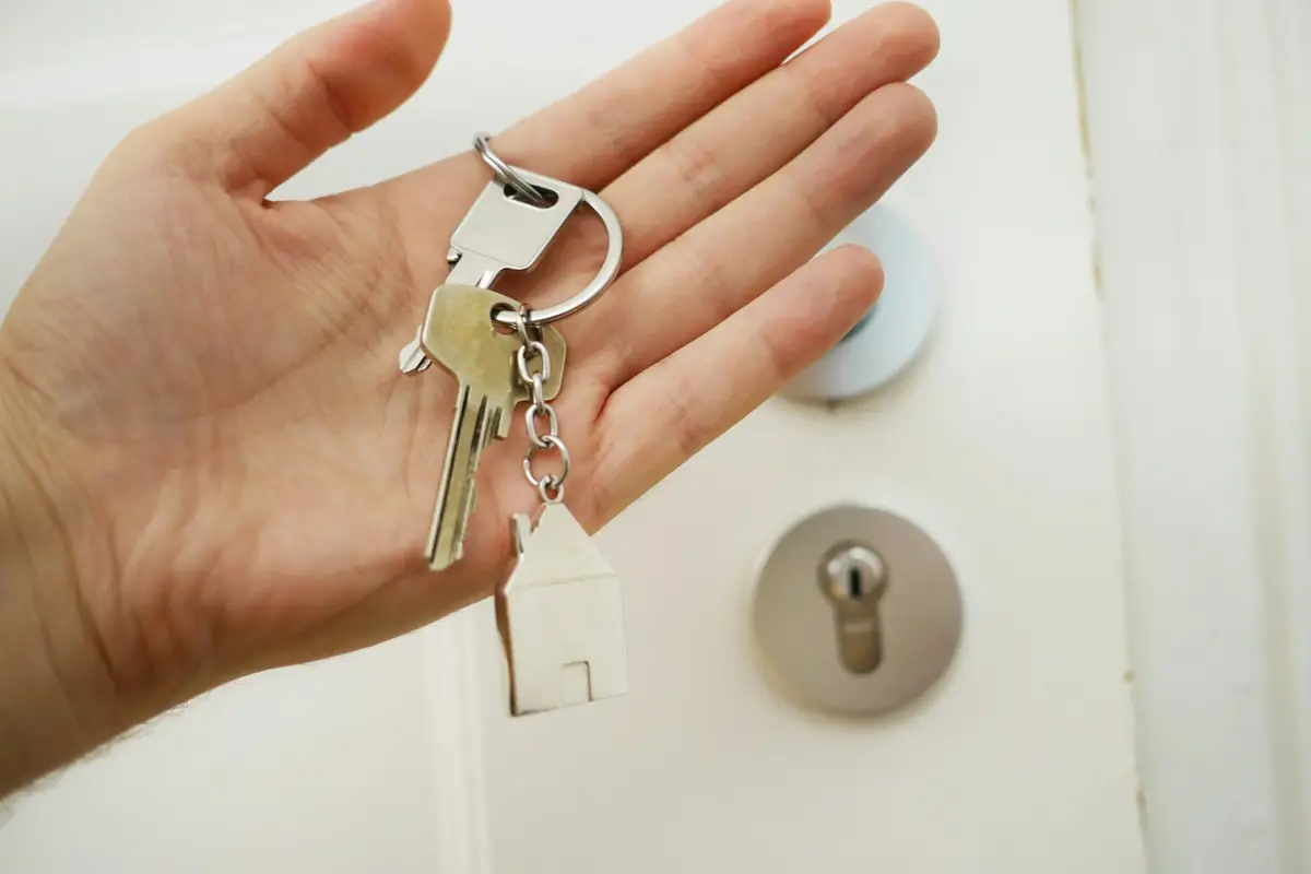 Hand holding a set of keys in front of a door lock