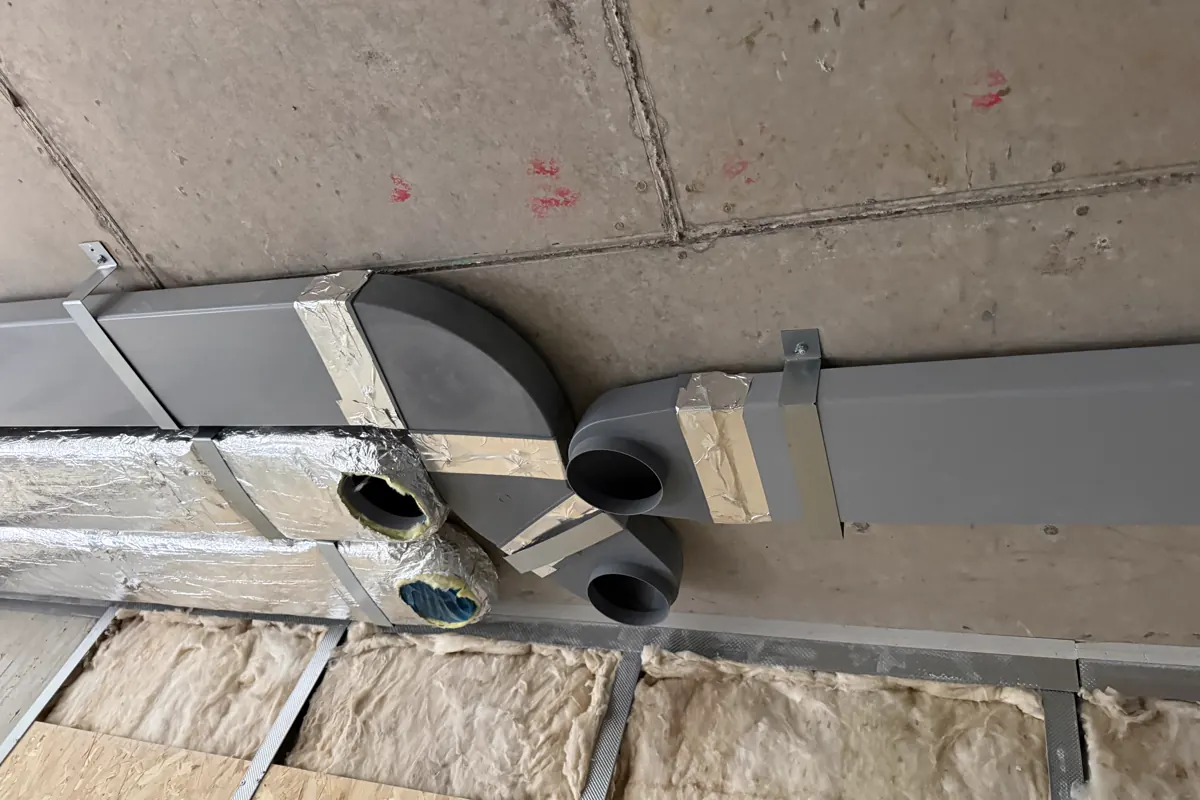 Rectangular ventilation ductwork and branches installed below a concrete soffit