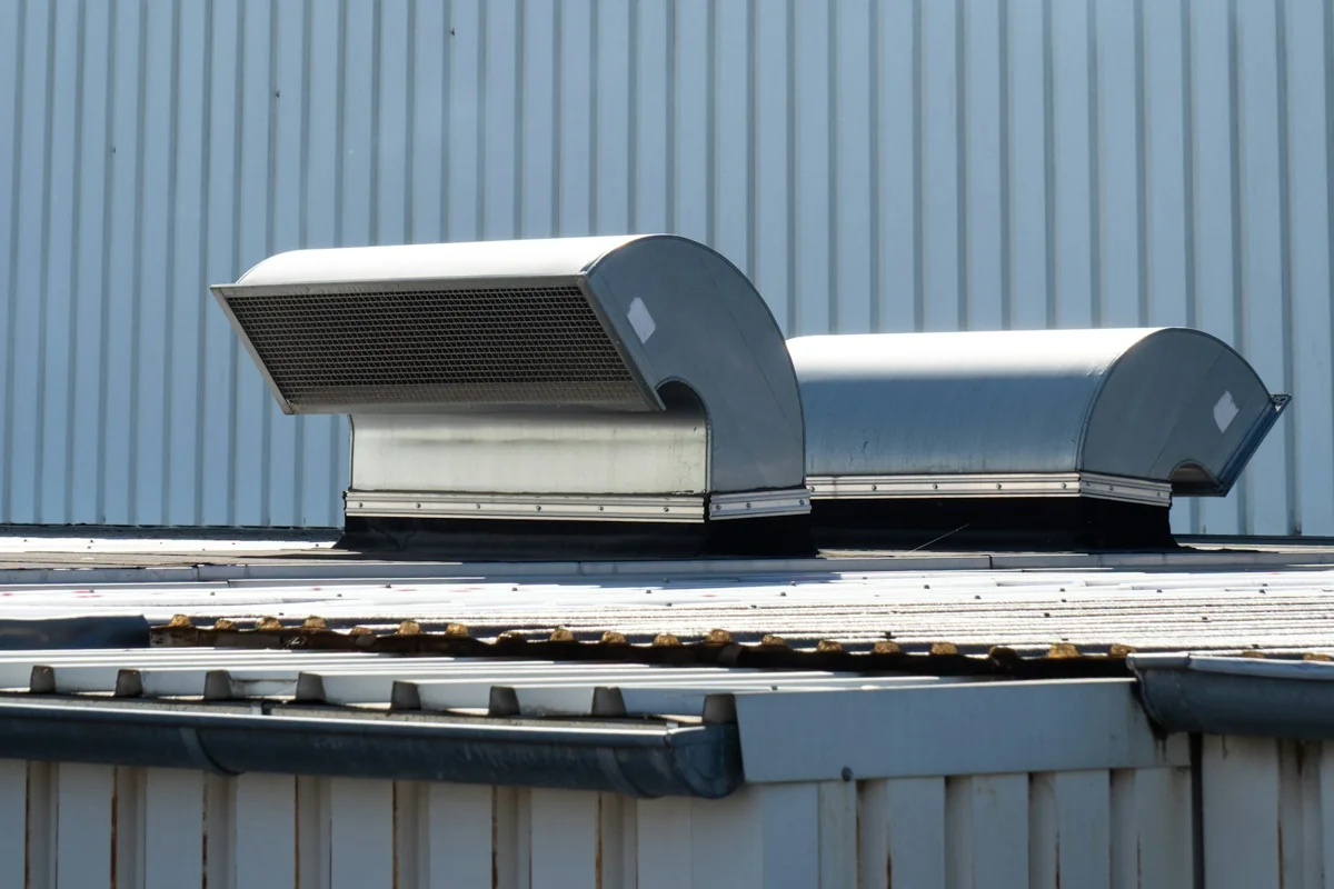 Two metal ventilation units mounted on a commercial building roof